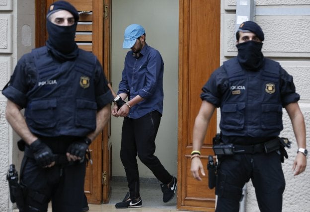 Uno de los detenidos por los ataques, custodiado por los agentes.