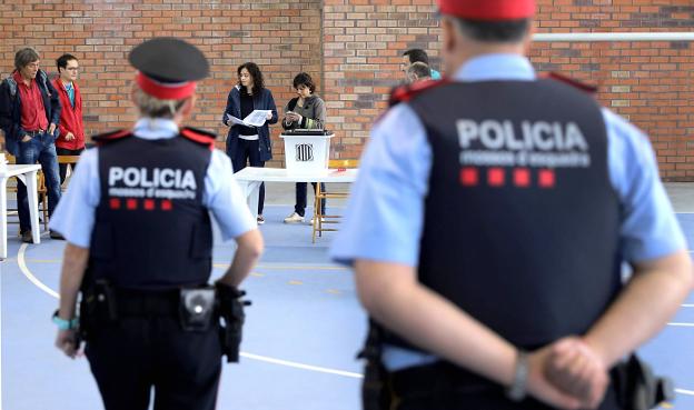 Una pareja de los Mossos observa el interior de un polideportivo habilitado el pasado 1-0 para votar en el referéndum ilegal. / c. manso / afp