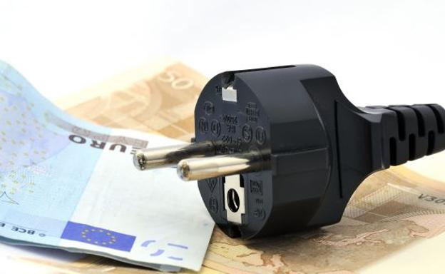 Clavija de un enchufe eléctrico y billetes de 20 euros./Fotolia