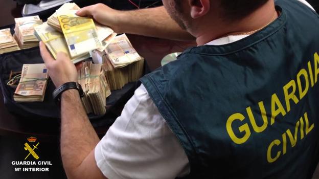 Un guardia civil cuenta billetes intervenidos en una operación antidroga. / LP