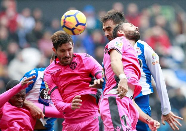 Campaña cabecea un balón en presencia de su compañero Morales y del deportivista Adrián. / efe