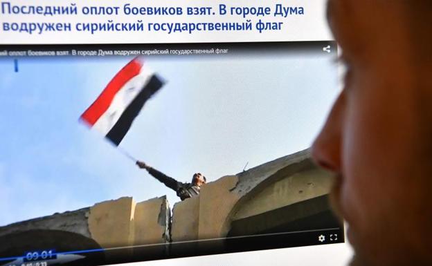 Espectador ruso observa la imagen de la bandera siria en Duma./Afp