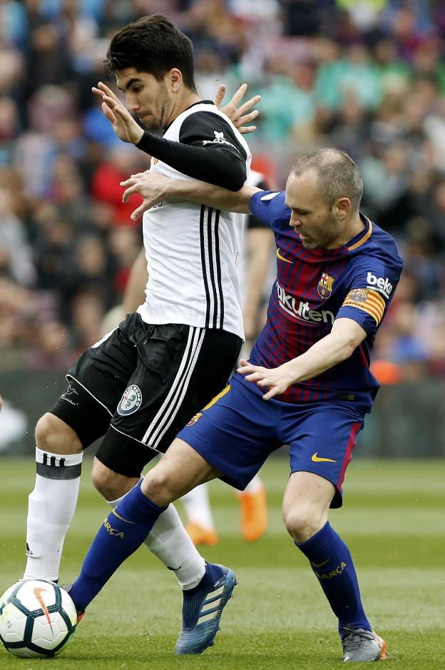Carlos Soler trata de robarle el balón a Iniesta. / EFE/Andreu Dalmau
