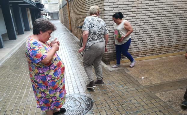 Tres vecinas de la víctima junto a los restos de sangre, en la calle Rosa Estruch de Valencia./J. MARTÍNEZ