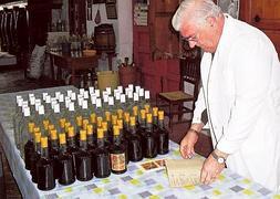 Juan Juan Micó hojea, junto a licores recién embotellados, el libro de sus fórmulas secretas, que guarda en una caja fuerte. / V. Lladró/