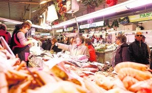Varias personas comprando en uno de los puestos del mercado central de Castellón. :: LP/