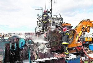 Los bomberos trabajan en la extinción del incendio en la embarcación. :: LP/