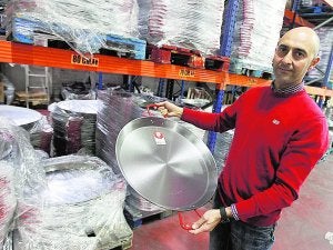 1955. Varios operarios fabrican paellas como se hacían entonces, a 'martell'. Moderna. A. García muestra una de sus paellas en la fábrica. :: JESÚS SIGNES/
