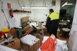 Un agente de la Policía Local inspecciona las instalaciones del taller ilegal de confección, ayer, en la calle La Serratella de Valencia./