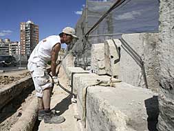 Un operario mueve, ayer, una de las piedras sillares del puente de Serranos./