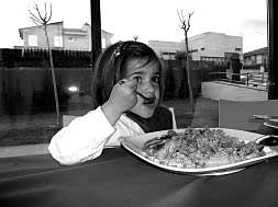 Una niña comiendo un plato de arroz./