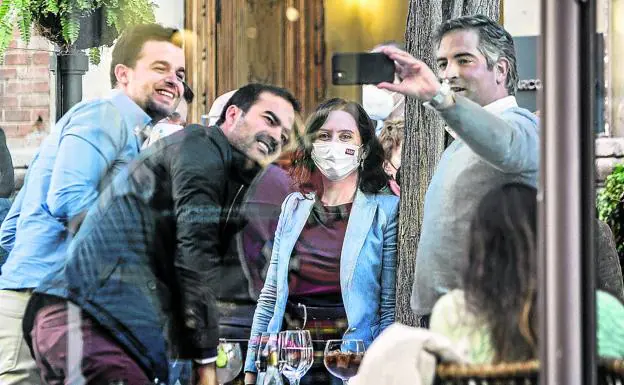 Isabel Díaz Ayuso se hace un selfie con varios admiradores sin mascarilla en un terraza del centro de Madrid./Europa Press