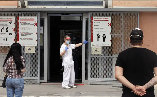 Dos usuarios y un profesional médico a las puertas de un centro de salud.