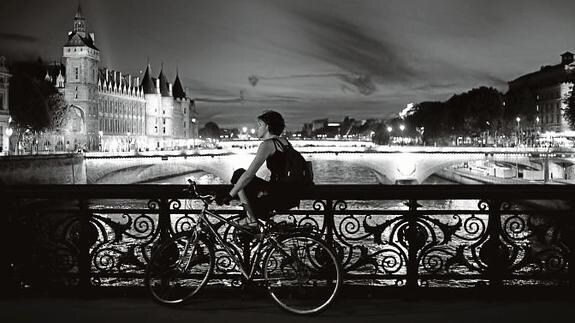 Una joven contempla la magia nocturna sobre uno de los 37 puentes del río Sena./